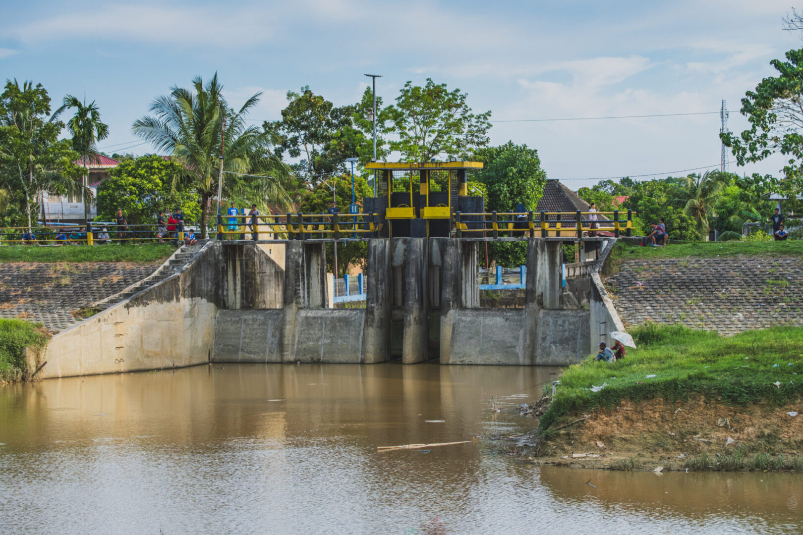 Water gate with surrounding greenery and people.