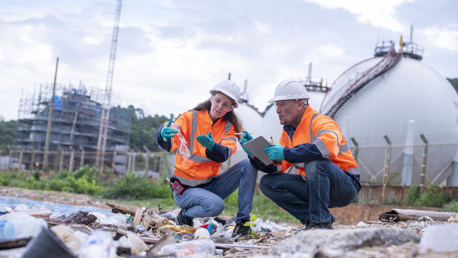 Workers inspecting landfill in safety gear.