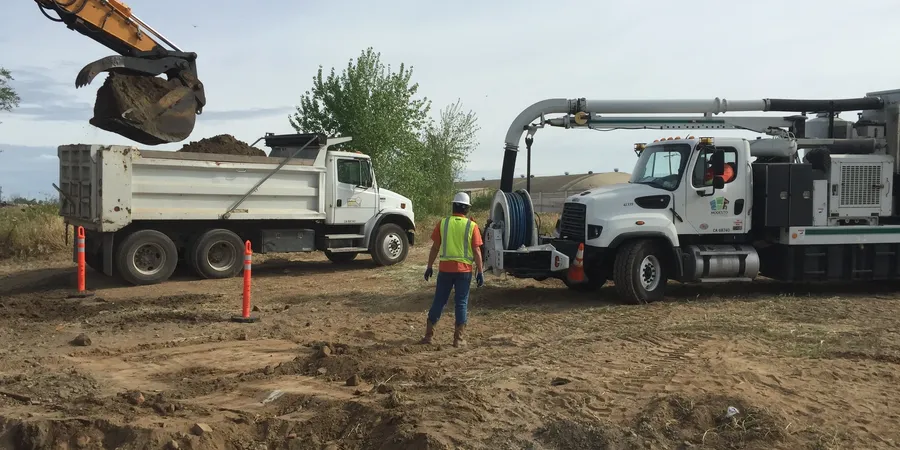 Construction site with trucks and worker.