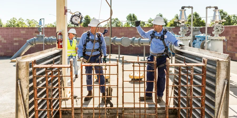 Workers inspecting industrial site with safety gear.
